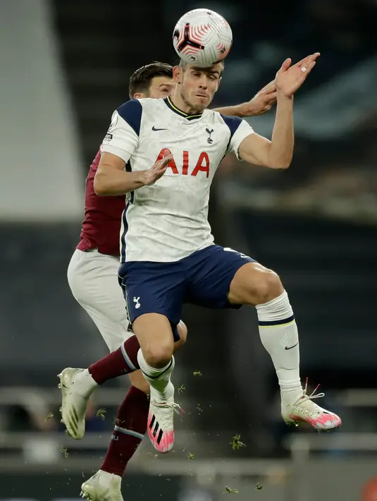 Penyerang Tottenham Hotspur, Gareth Bale melompat saat berebut bola dengan pemain West Ham, Aaron Cresswell dalam laga Liga Inggris di Tottenham Hotspur Stadium, Minggu (18/10/2020). Laga yang berakhir dramatis 3-3 itu diwarnai debut bintang anyar Tottenham, Gareth Bale. (AP photo/Matt Dunham, Pool)