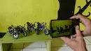 Seorang pekerja memotret miniatur sepeda motor di bengkel kerjanya di Kelurahan Serua, Tangerang Selatan, Banten (10/10/2020). Di sana, miniatur sepeda motor yang terbuat dari bahan-bahan daur ulang dijual kepada pelanggan sebagai hadiah atau hiasan. (Xinhua/Agung Kuncahya B.)