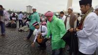 Aa Gym berinisiatif memunguti sampah yang masih tersisa di lapangan Monas. (Liputan6.com/Nafiysul Qodar)