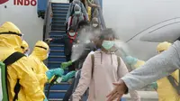 Petugas menyemprotkan cairan disinfektan ke WNI yang dievakuasi dari Wuhan, China saat tiba di bandara internasional Hang Nadim, Batam, Minggu (2/2/2020). Sebanyak 245 WNI di Wuhan dievakuasi ke Indonesia terkait merebaknya virus corona di kota tersebut. ((Photo by Handout/Indonesian Embassy/AFP)