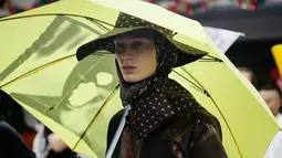 Seorang model mengenakan rancangan desainer Raf Simons dalam acara Men’s Fashion Week di New York, Selasa (11/7). Topi dan payung menjadi aksesoris andalan Raf Simons dalam rancangannya. (AP/Frank Franklin)