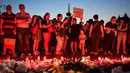 Warga menyalakan lilin untuk memperingati gadis berusia 15 tahun Alexandra yang terbunuh di depan Kementerian Dalam Negeri Rumania di Bucharest (27/7/2019). Seorang tersangka berusia 65 tahun yang ditemukan di gedung itu masih ditahan untuk diinterogasi. (AFP Photo/Daniel Mihailescu)