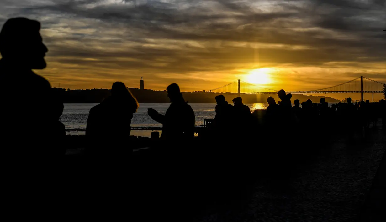 Orang-orang menikmati matahari terbenam di Ribeira das Naus di Lisbon (17/12). Lisboa atau Lisbon merupakan ibu kota  Portugal. (AFP Photo/Patricia De Melo Moreira)