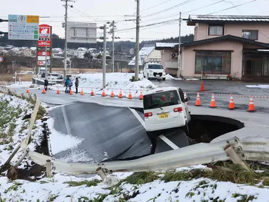 Sebuah kendaraan terparkir di tepi jalan yang runtuh di Kota Tohoku, Prefektur Aomori, Jepang, pada Selasa 9 Desember 2025. Gempa besar mengguncang lepas pantai utara Jepang. (JIJI Press/Japan OUT/AFP)