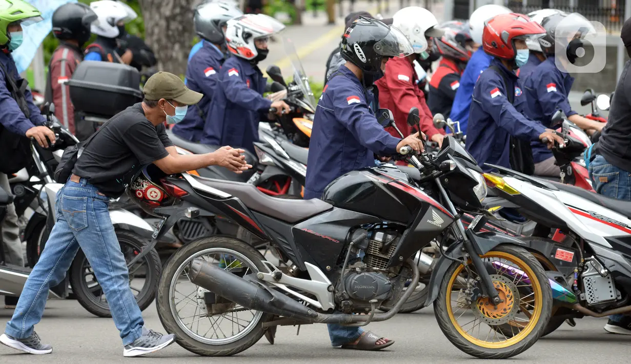 Buruh mendorong sepeda motor mereka saat melakukan aksi unjuk rasa di kawasan Patung Kuda, Jakarta, Rabu (10/11/2021). Buruh menuntut pemerintah untuk mencabut UU Cipta Kerja dan meminta Presiden Joko Widodo atau Jokowi untuk mundur. (merdeka.com/Imam Buhori)