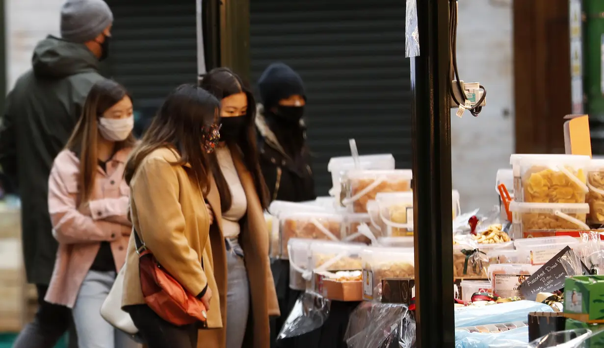 Pembeli makanan mengenakan masker saat berbelanja di Borough Market di London selatan selama penguncian nasional (lockdown) ketiga Inggris, Selasa (12/1/2021). Borough Market menjadi tempat pertama yang mewajibkan pemakaian masker di luar ruangan. (AP Photo/Alastair Grant)