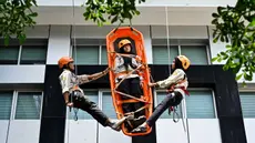 Mahasiswa mengikuti simulasi Vertical Rescue atau evakuasi vertikal selama latihan gempa bumi dan bencana di Universitas Syiah Kuala, Banda Aceh pada Selasa 21 Oktober 2025. (CHAIDEER MAHYUDDIN/AFP)