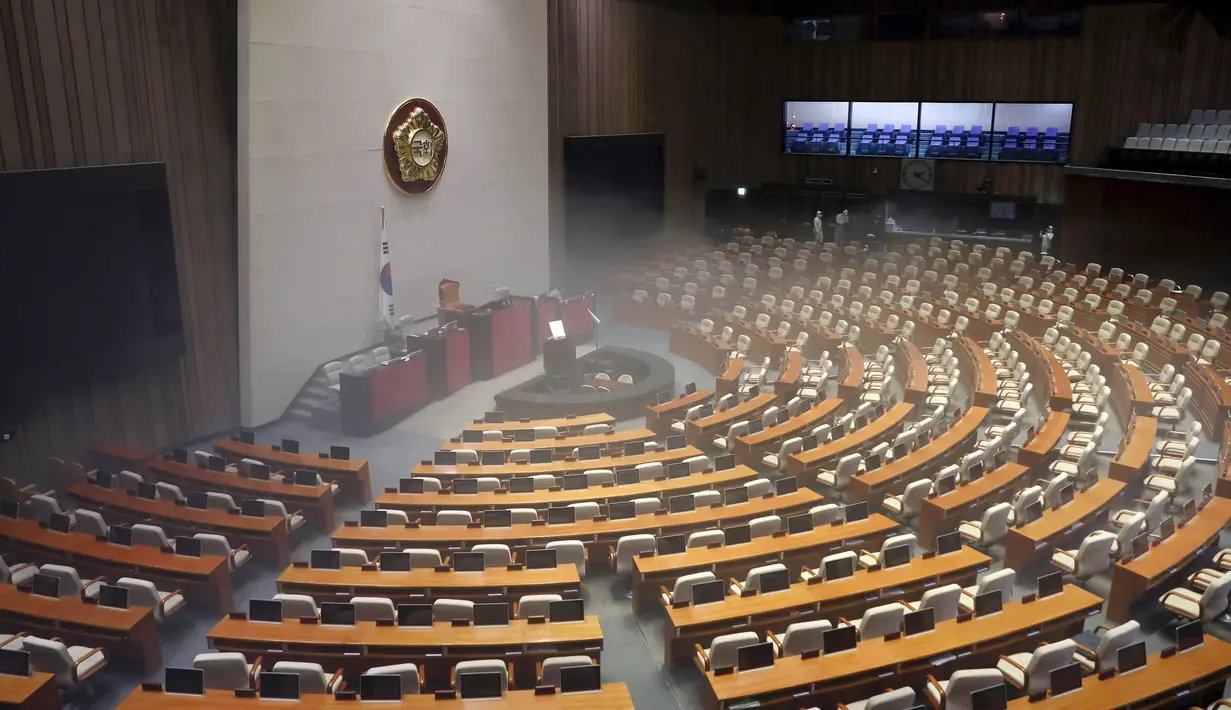 Pekerja dari Asosiasi Pengendalian Hama Korea menyemprotkan disinfektan sebagai  tindakan pencegahan terhadap penyebaran virus corona COVID-19, di Majelis Nasional Seoul (25/2/2020). (AFP/Yonhap)