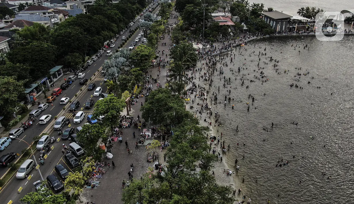Foto udara menunjukkan keramaian pengunjung di Pantai Karnaval Ancol, Jakarta, Jumat (14/5/2021). Pemprov DKI Jakarta pada libur Lebaran 2021 membuka sejumlah tempat wisata, salah satunya Ancol. (Liputan6.com/Johan Tallo)