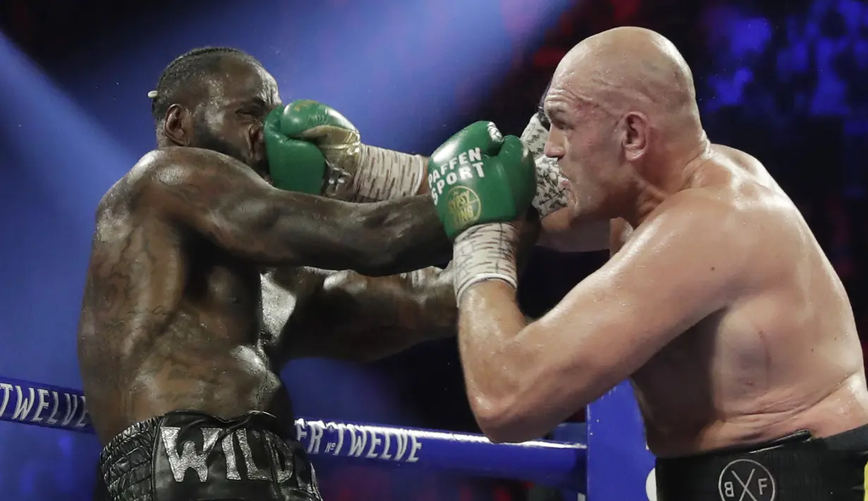 Petinju Inggris Tyson Fury melancarkan pukulan ke arah wajah petinju AS Deontay Wilder pada pertandingan tinju kelas berat WBC di Las Vegas (23/2/2020). Tyson Fury berhasil memenangkan pertarungan di ronde ketujuh. (AP Photo/Isaac Brekken)