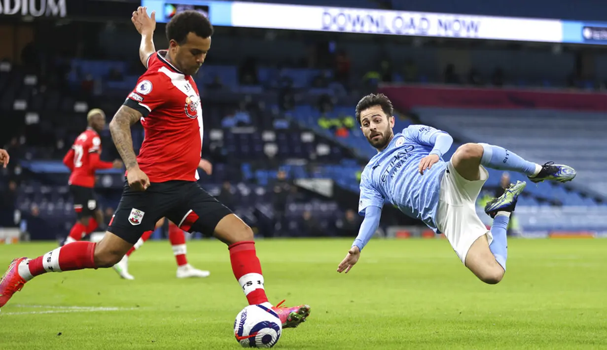 Pemain Southampton Ryan Bertrand (kiri) menendang bola di depan pemain Manchester City Bernardo Silva pada pertandingan Liga Inggris di Etihad Stadium, Manchester, Inggris, Rabu (10/3/2021). Manchester City menang 5-2. (Clive Brunskill/Pool via AP)