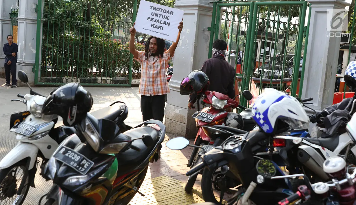 Aktivis Koalisi Pejalan Kaki (KPK) melakukan aksi sambil membawa poster himbauan di sepanjang trotoar kawasan Monas, Jakarta, Jumat (28/7). (Liputan6.com/Immanuel Antonius)