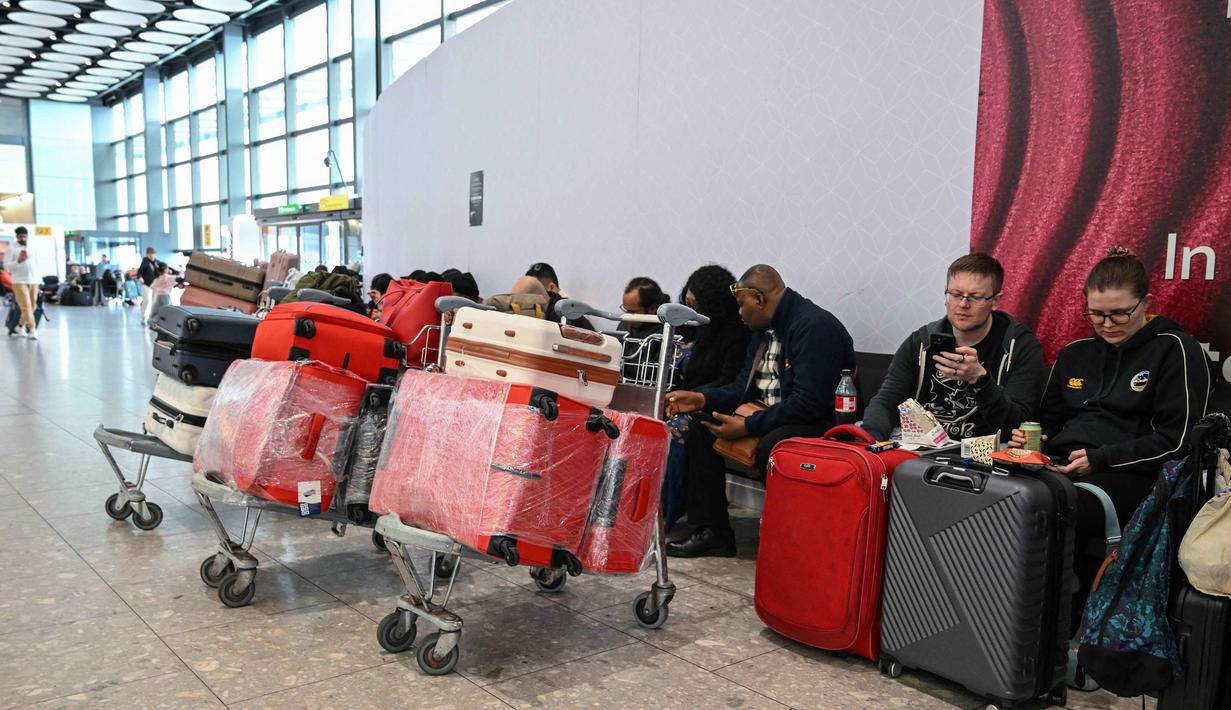 Pihak maskapai menjelaskan bahwa keputusan pembatalan dilakukan sebagai bentuk penerapan standar keamanan dan keselamatan penerbangan. Tampak dalam foto, para penumpang duduk menunggu kabar tentang penerbangan di Terminal 4 Bandara Heathrow, London pada Minggu 1 Maret 2026. (JUSTIN TALLIS/AFP)