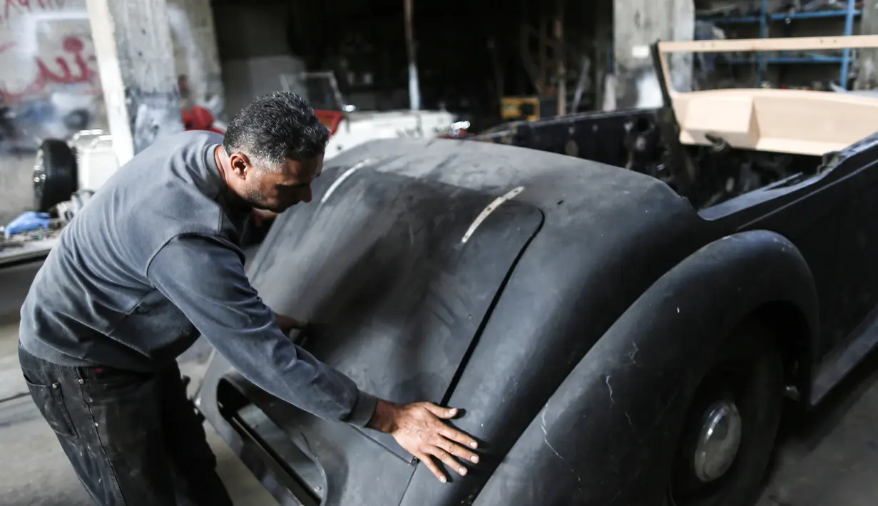 Munir Shindy saat merestorasi mobil klasik di bengkelnya di Kota Gaza (28/10/2019). Pria 40 tahun ini sudah bekerja merestorasi mobil selama 12 tahun. Mobil terakhir yang dikerjakan Shindi adalah Armstrong Siddeley Hurricane 1946. (AFP Photo/Mahmud Hams)