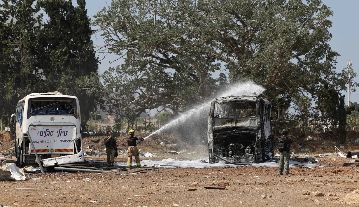 Seorang petugas pemadam kebakaran Israel memadamkan bangkai bus di lokasi jatuhnya rudal Iran di sebuah depot bus di Herzliya dekat Tel Aviv pada 17 Juni 2025. (Jack GUEZ/AFP)