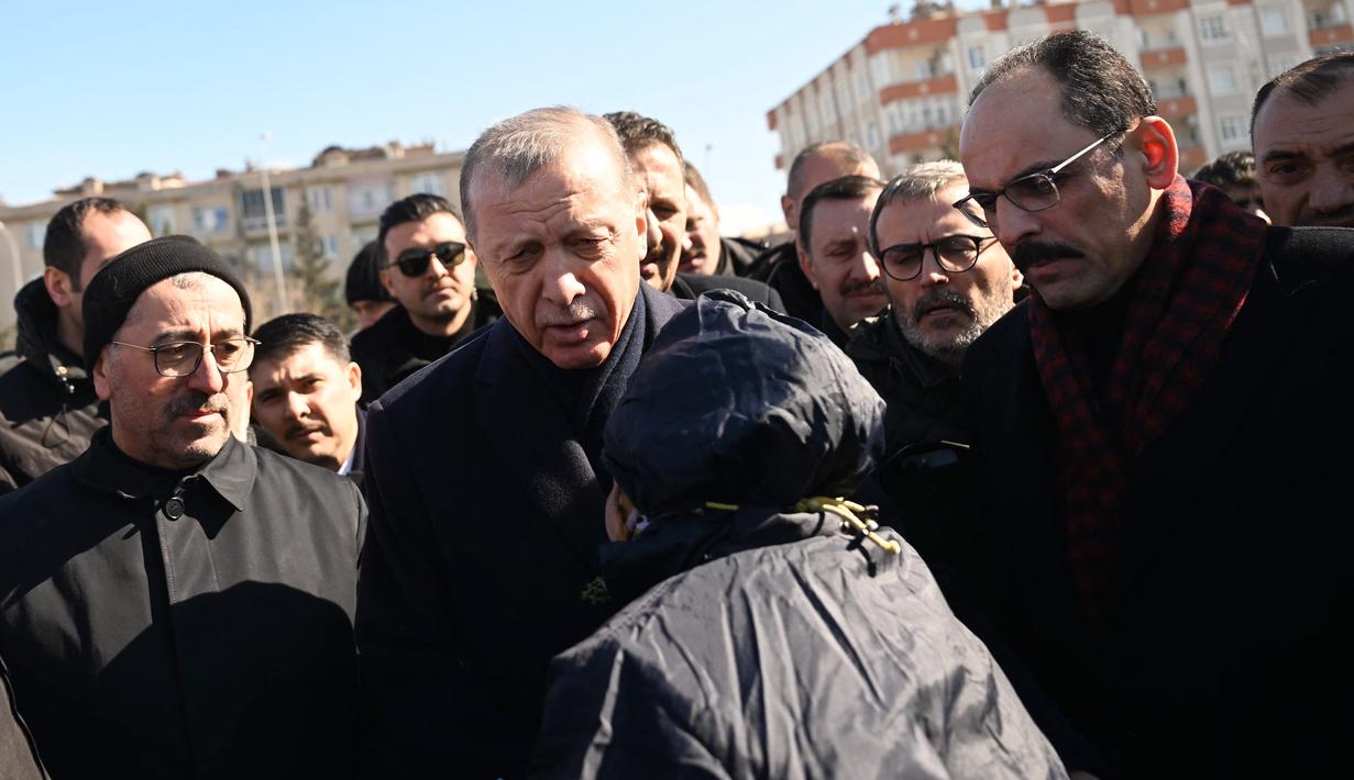Presiden Turki Recep Tayyip Erdogan bertemu dengan penduduk yang mengungsi di bawah tenda yang didirikan pemerintah selama kunjungannya ke kota Kahramanmaras di tenggara Turki, dua hari setelah gempa kuat melanda wilayah tersebut, pada 8 Februari 2023. Warga masih banyak yang mengungsi takut terjadi gempa susulan. (AFP/Ozan Kose)