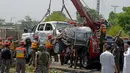 Petugas mengangkat kendaraan yang hancur akibat serangan bom bunuh diri di Peshawar, Pakistan, Senin (17/7). Menurut polisi setempat Bom bunuh diri tersebut menewaskan dua orang dan melukai enam lainnya. (AFP Photo/Abdul Majeed)
