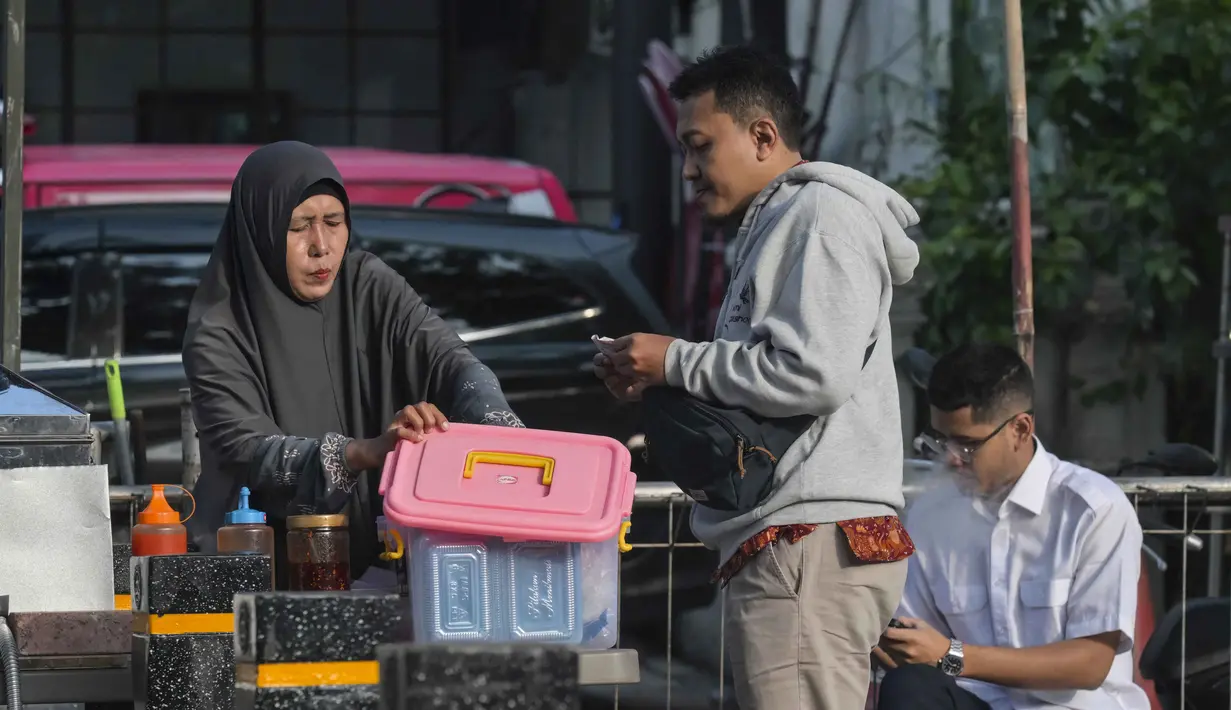 Hal tersebut mengingat sebagian besar pelaku usaha mikro berasal dari kelompok berpenghasilan rendah dan bekerja di sektor informal. Tampak dalam foto, seorang wanita menyajikan sarapan kepada pelanggannya di sebuah warung pinggir jalan, Jakarta, Senin 4 Mei 2026. (BAY ISMOYO/AFP)