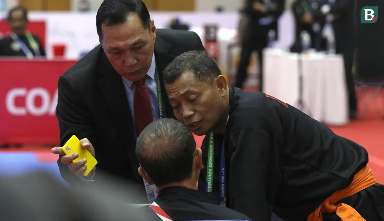 Sempat ada insiden antara Ketua Harian PB Ikatan Pencak Silat Indonesia (IPSI), Benny Sumarsono (kiri) dengan pelatih pencak silat Indonesia,  Bondan. Benny lalu meminta Bondan untuk keluar. Dia menunjuk-nunjuk pintu keluar venue silat SEA Games 2021, untuk meminta Bondan segera angkat kaki dari lapangan. (Bola.com/Ikhwan Yanuar)
