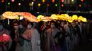 Umat Buddha Korea Selatan mengenakan masker membawa lentera lotus berwarna-warni selama upacara pencahayaan untuk merayakan ulang tahun Buddha yang akan datang pada 8 Mei, di Seoul, Korea Selatan (5/4/2022). (AP Photo/Lee Jin-man)