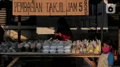 Seorang anak berdiri di depan tumpukan takjil yang akan dibagikan di Jalan Cempaka Putih Raya, Jakarta, Senin (11/5/2020). Setiap hari selama Ramadan, masyarakat sekitar membagikan 350 takjil kepada warga kurang mampu dan terdampak virus corona COVID-19. (Liputan6.com/Johan Tallo)