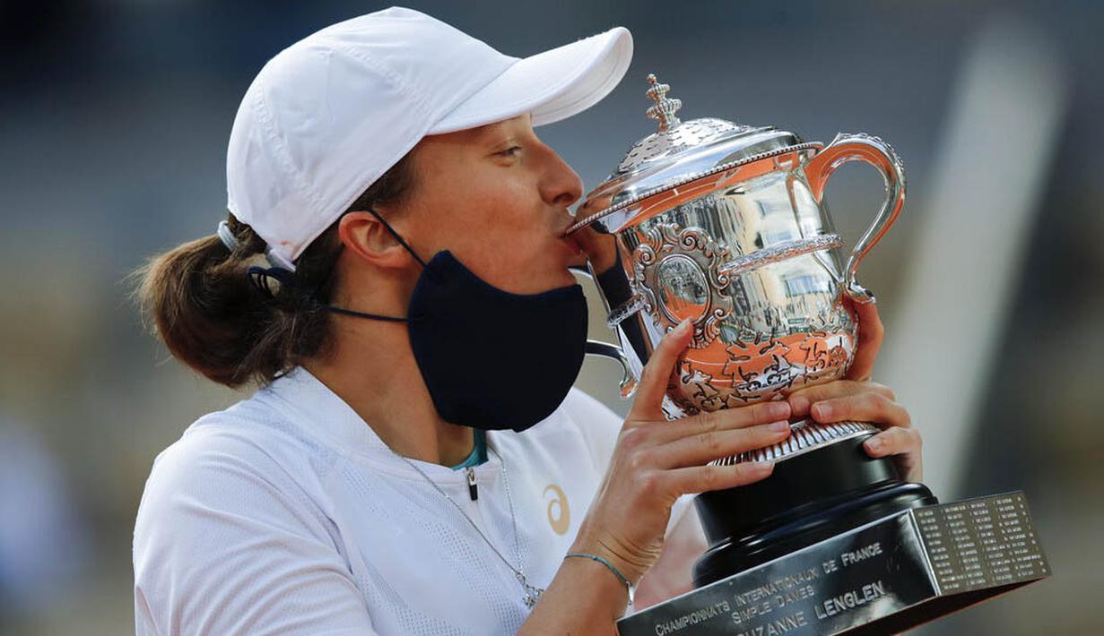 Petenis Polandia, Iga Swiatek, melakukan selebrasi mencium trofi usai menjuarai Grand Slam Prancis Terbuka di Paris, Sabtu, Sabtu (10/10/2020). Petenis berusia 19 tahun itu menaklukkan wakil Amerika Serikat, Sofia Kenin, dua set langsung 6-4 dan 6-1. (AP Photo/Michel Euler)