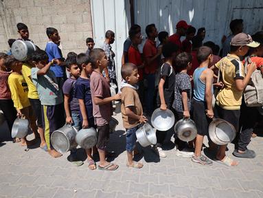 Anak-anak Palestina mengantre untuk menerima makanan panas dari dapur amal kamp pengungsi Nuseirat di Jalur Gaza yang dikepung Israel pada 11 September 2025. (Eyad BABA/AFP)