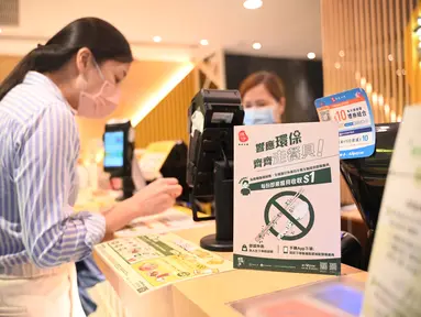 Sebuah tanda bertuliskan bahwa restoran tersebut tidak akan menyediakan peralatan makan plastik sekali pakai kepada pelanggan di Hong Kong, Senin (22/4/2024). (Peter PARKS / AFP)