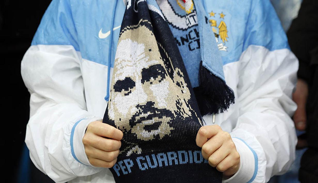Fans memakai syal bergambar pelatih Manchester City musim depan, Josep Guardiola, saat laga melawan Leicester di Stadion Ettihad, Inggris, Sabtu (6/2/2016). City Takluik 1-3 dari Leicester. (Reuters/Jason Cairnduff)