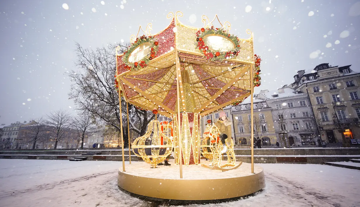 Seorang wanita menaiki komidi putar di Warsawa, Polandia, pada 10 Desember 2020. Warsawa menyambut salju pertamanya tahun ini pada Kamis (10/12). (Xinhua/Jaap Arriens)