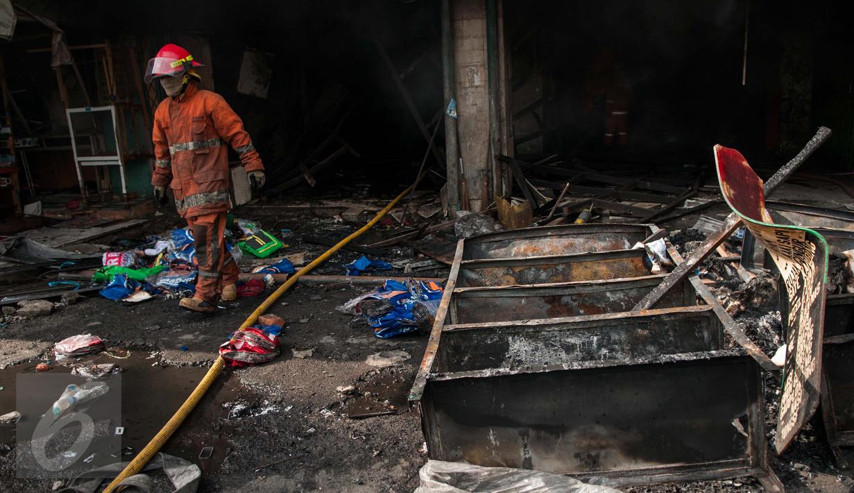 Petugas Damkar melintas di dekat bangunan yang terbakar di Pasar Senen, Jakarta, Kamis (19/1). Penyebab kebakaran masih dalam tahap penyelidikan. (Liputan6.com/Gempur M Surya)