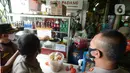 Petugas gabungan menempelkan segel penutupan sementara salah satu tempat makan di Pasar Pramuka, Jakarta, Kamis (24/9/2020). Upaya mencegah penularan virus corona terus dilakukan dengan merazia penggunaan masker dan tempat usaha makan yang masih melayani makan di tempat. (merdeka.com/Imam Buhori)