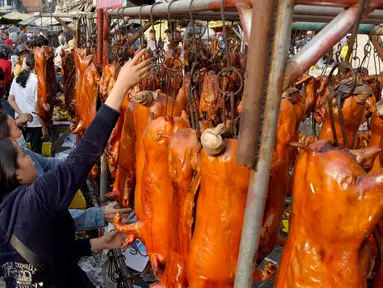 Seorang pedagang menggantung babi panggang di pasar di Phnom Penh, Kamboja (4/2). Menyambut Tahun Baru Imlek, warga Kamboja mempersiapkan daging babi panggang untuk sajian makan. (AFP Photo/Tang Chhin Sothy)