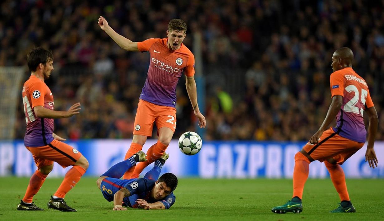 Striker Barcelona, Luis Suarez, terjatuh saat dilanggar pemain Manchester City, John Stones, dalam laga Grup C Liga Champions di Camp Nou, Barcelona, Kamis (20/10/2016) dini hari WIB. (AFP/Lluis Gene)