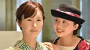 Seorang pengunjung berpose bersama robot humanoid ChihiraAico (kiri) yang mengenakan kimono Jepang di Tokyo pada 20 April 2015. Robot ini bisa tersenyum, menyanyi dan memberikan bimbingan pada pengunjung. (AFP PHOTO/KAZUHIRO)