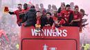 Para pemain Liverpool melambaikan tangan dan memegang dua trofi yaitu Piala FA dan Piala Liga Inggris di atas bus terbuka saat parade menyusuri jalan-jalan kota Liverpool pada Minggu (29/05/2022) waktu setempat. (AFP/Oli Scarff)