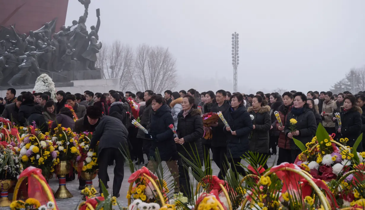 Penduduk Pyongyang membawa bunga untuk diletakan di depan patung pemimpin Korea Utara Kim Il Sung dan Kim Jong Il selama Hari Peringatan Nasional di Bukit Mansu, Pyongyang (17/12).  (AFP Photo/Kim Won Jin)