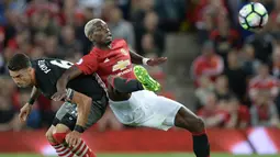 Gelandang Manchester United. Paul Pogba, berebut bola dengan bek Southampton, Jose Fonte. Pertandingan ini merupakan laga perdana Paul Pogba setelah kembali berseragam Setan Merah. (AFP/Oli Scarff)