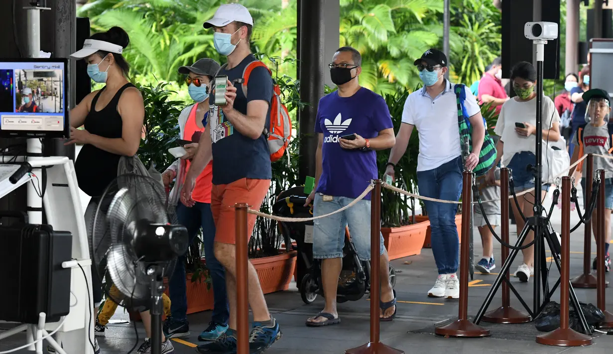 Pengunjung menunjukkan kode masuk mereka saat melalui area pemeriksaan suhu pada hari pertama pembukaan Kebun Binatang Singapura, Senin (6/7/2020). Kebun binatang yang hampir tiga bulan ditutup akibat pandemi virus corona ini dibuka kembali dengan penerapan protokol kesehatan. (Roslan RAHMAN/AFP)