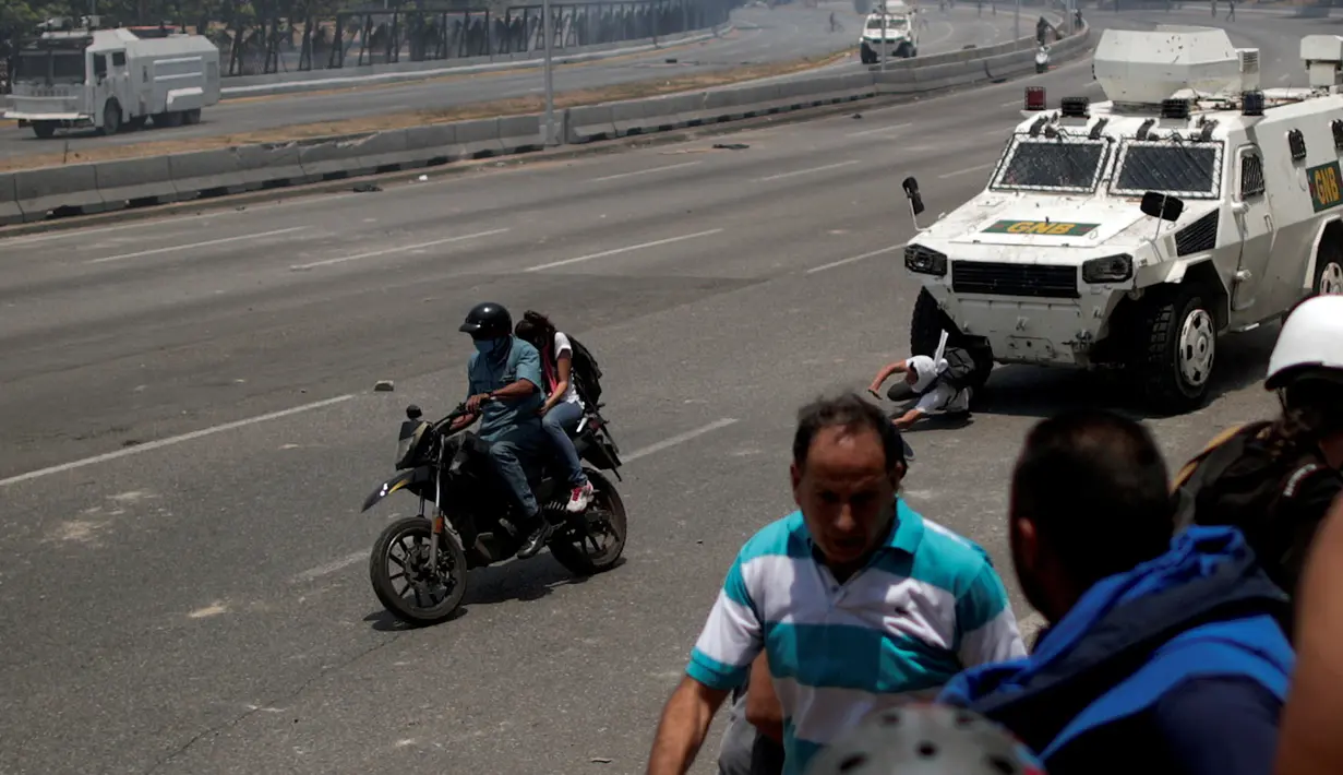 Seorang pengunjuk rasa pendukung oposisi, Luis Alejandro (26) terjatuh saat ditabrak kendaraan taktis Garda Nasional Venezuela di luar pangkalan militer 'La Carlota' di Caracas, Venezuela (30/4/2019). Luis ditabrak oleh tentara yang menghalau aksi demonstrasi tersebut. (Reuters/Ueslei Marcelino)