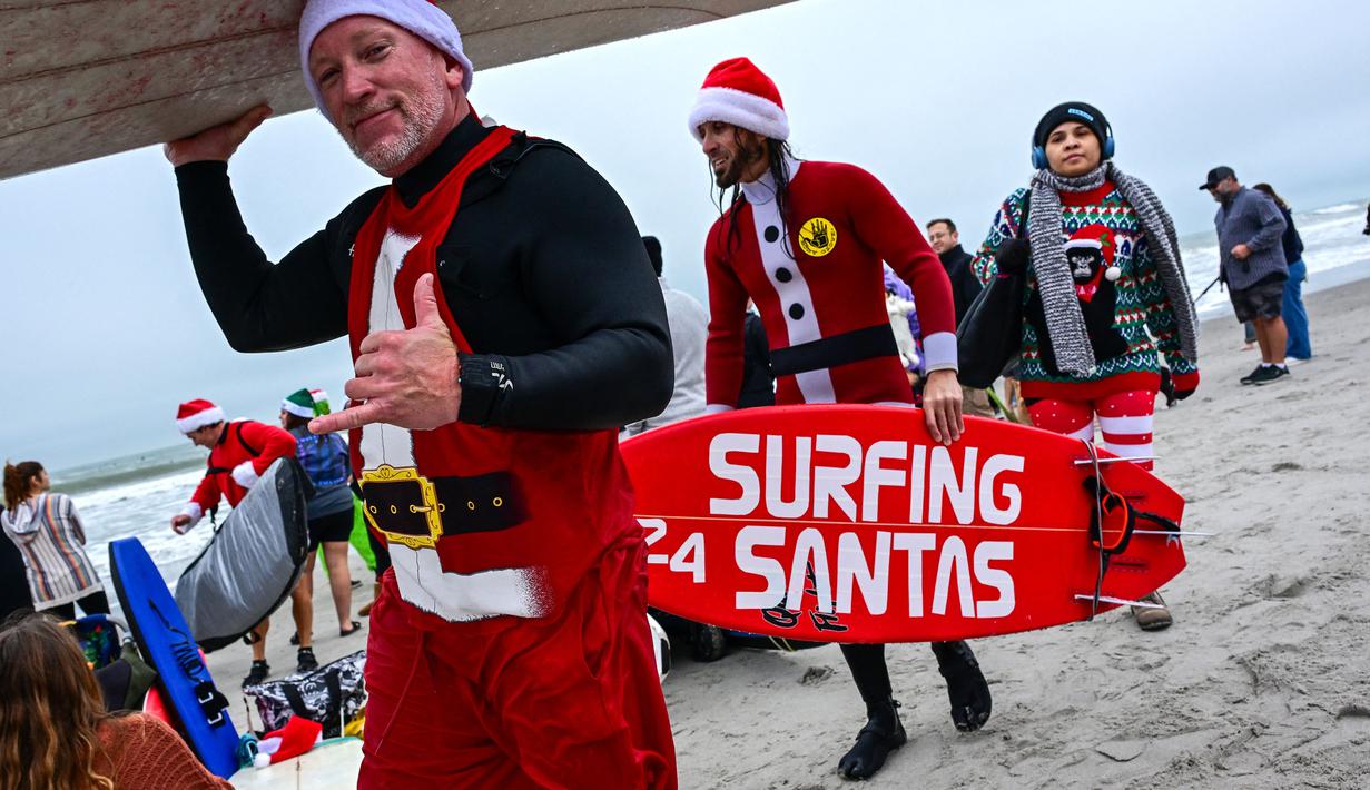 Sejumlah pengunjung berkostum Sinterklas bersiap untuk berselancar dalam acara Surfing Santa yang berlangsung di Pantai Cocoa, Florida, Amerika Serikat, Selasa (24/12/2024) waktu setempat. (AFP/Giorgio Viera)