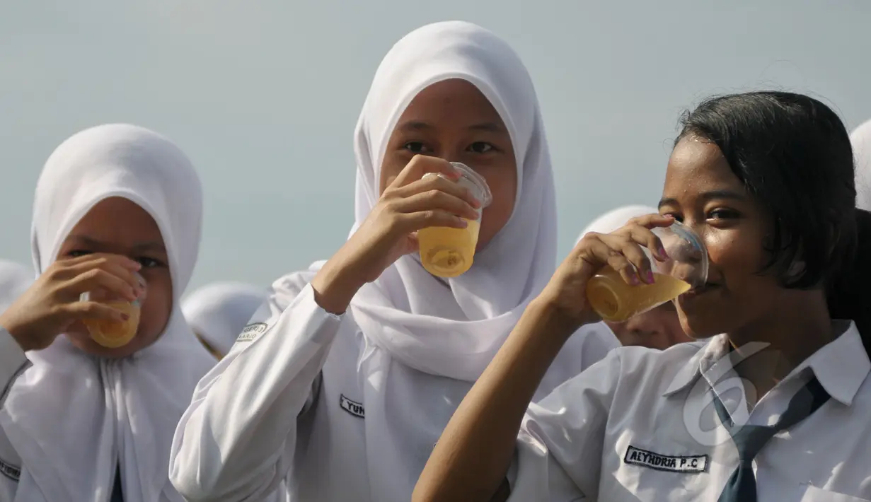 <p>Sejumlah pelajar saat minum jamu bersama di Alun-Alun Satya Negara Sukoharjo, Jawa Tengah, Rabu (1/4/2015). Kegiatan tersebut dalam rangka pelestarian jamu ke masyarakat nasional maupun internasional. (Liputan6.com/Johan Tallo)</p>