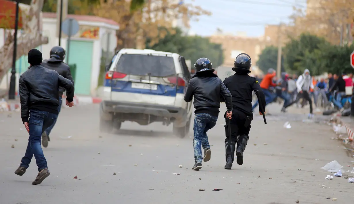 Polisi mengejar pengunjuk rasa yang melakukan aksi protes di luar kantor pemerintah setempat di Kasserine, Tunisia, Kamis (21/1). Para pengangguran muda turun ke jalan memprotes keterpurukan ekonomi dan sulitnya lapangan kerja. (REUTERS/Amine Ben Aziza)