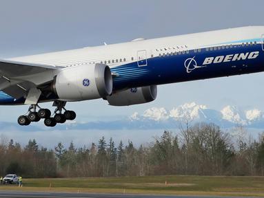 Pesawat Boeing 777X lepas landas pada penerbangan pertamanya dengan latar belakang Pegunungan Olimpiade di Paine Field, Everett di Washington, Sabtu (25/1/2020). Untuk pertama kalinya, Boeing sukses melakukan ujicoba terbang perdana pesawat jet bermesin ganda terbesar di dunia. (AP/Ted S. Warren)