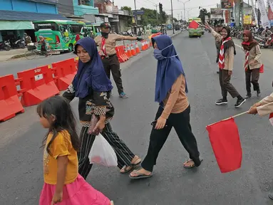 Anggota Pramuka membantu menyebrangi warga saat mengatur lalu lintas di jalur mudik kawasan pasar Surodadi, Tegal  Jawa Tengah, Senin (3/6/2019). Puluhan anggota Pramuka  membantu polisi mengatur lalu lintas selama arus mudik maupun arus balik. (Liputan6.com/Herman Zakharia)