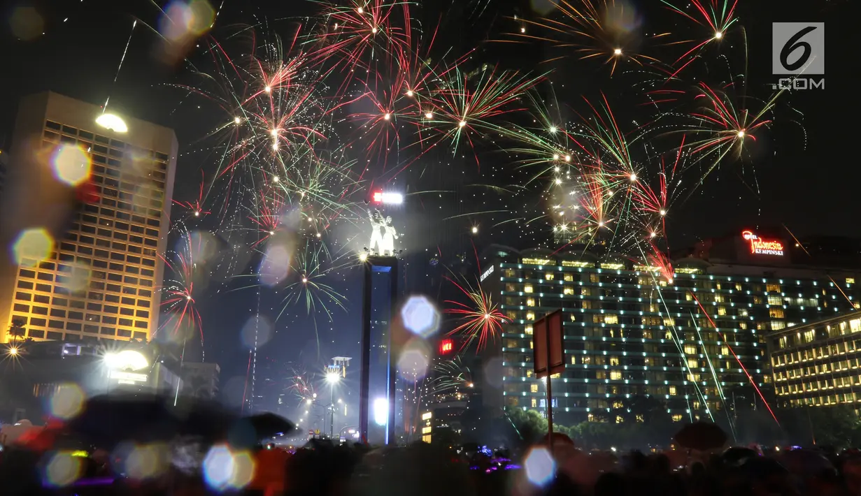Kembang api menghiasi malam pergantian tahun baru 2019 di kawasan Bundaran HI, Jakarta, Selasa (1/1). Hujan yang mengguyur Jakarta tidak menyurutkan warga menikmati kembang api tahun baru. (Liputan6.com/Angga Yuniar)