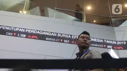Pengunjung melintas dilayar pergerakan saham di BEI, Jakarta, Senin (30/12/2019). Pada penutupan IHSG 2019 ditutup melemah cukup signifikan 29,78 (0,47%) ke posisi 6.194.50. (Liputan6.com/Angga Yuniar)