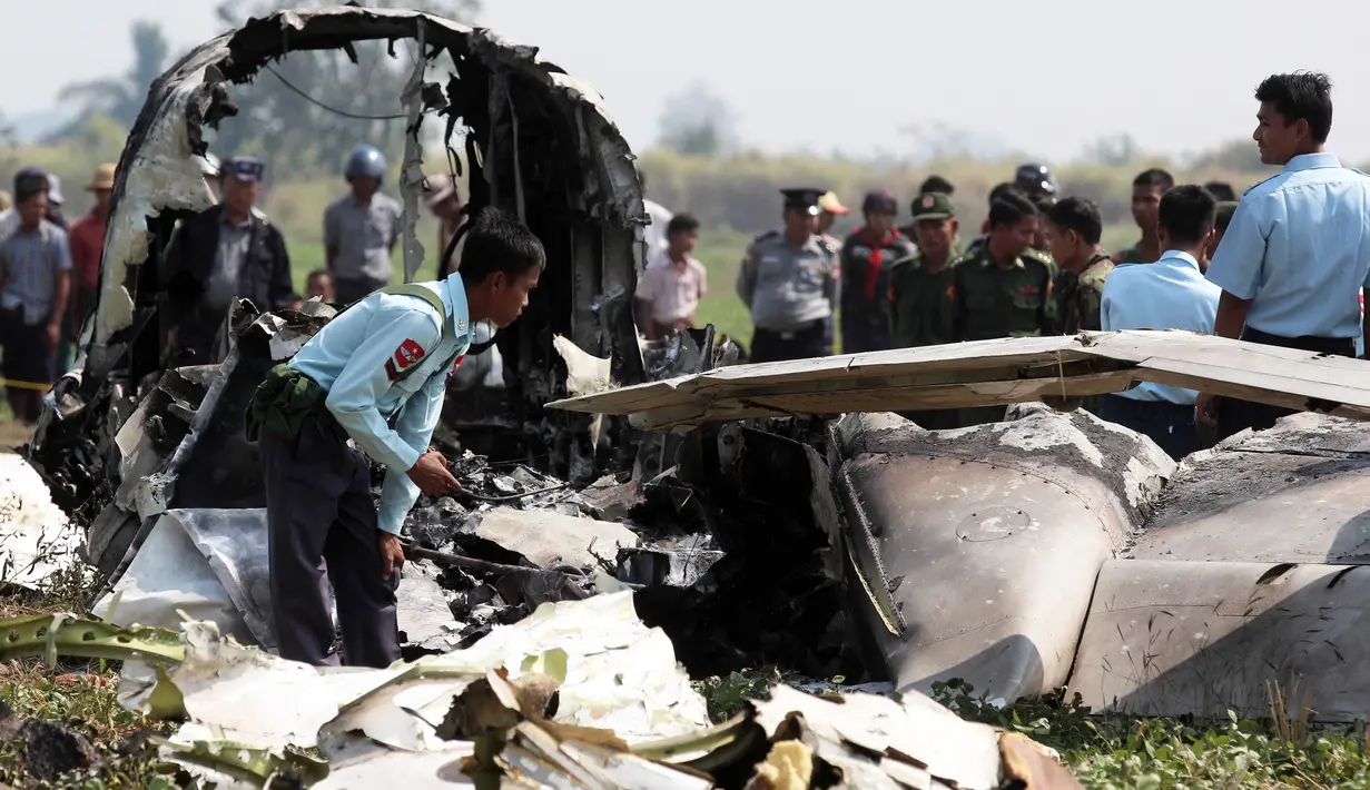 Petugas memeriksa puing pesawat militer yang jatuh sesaat setelah lepas landas di bandara Kota Naypidaw, Myanmar, Rabu (10/2). Pesawat penumpang jenis Beechcraft tersebut sedang membawa lima orang kru militer yang akan melakukan patroli rutin. (STR/AFP)