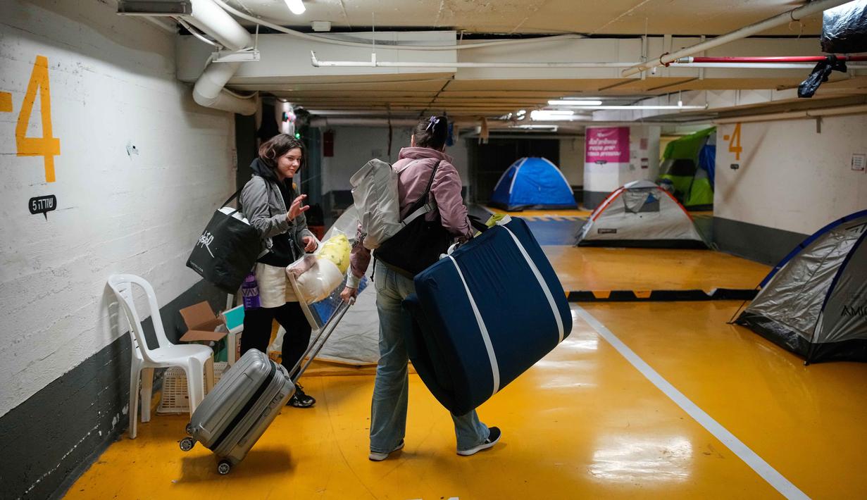 Orang-orang membawa barang-barang mereka saat meninggalkan tempat perlindungan bawah tanah tempat mereka tinggal selama perang dengan Iran, setelah pengumuman gencatan senjata selama dua minggu, di Tel Aviv, Israel, Rabu 8 April 2026. Presiden Amerika Serikat, Donald Trump, resmi mengumumkan gencatan senjata selama dua minggu antara Amerika Serikat, Iran, dan Israel pada Rabu 8 April 2026. (AP Photo/Ohad Zwigenberg)