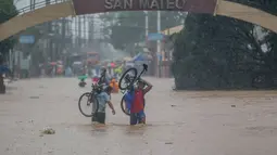 Sejumlah warga berjalan menembus genangan banjir yang diakibatkan oleh Topan Vamco di Provinsi Rizal, Filipina (12/11/2020). Topan Vamco membawa angin kencang dan hujan deras yang memicu tanah longsor, longsor batu, serta banjir bandang. (Xinhua/Rouelle Umali)